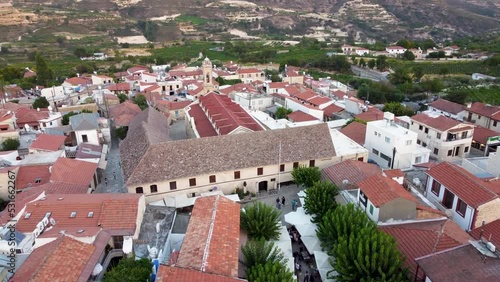 Aerial drone footage of traditional countryside village Omodos, Limassol, Cyprus. 360 orbit view of Timios Stavros (Holy Cross) monastery, tiled roof houses and balconies, narrow streets from above. photo