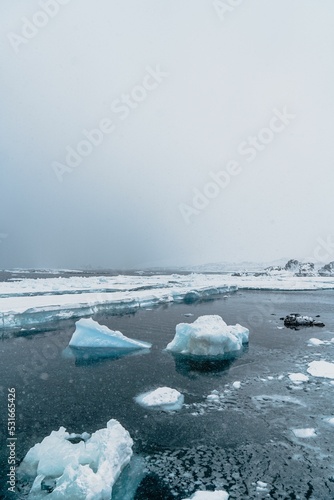 Vertical shot of the Carlini Antarctic snowy icebergs flowing in the ocean photo