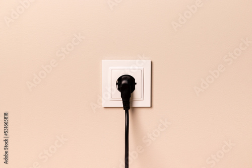 Foto White european electrical outlet with black plug inserted into it on modern beig