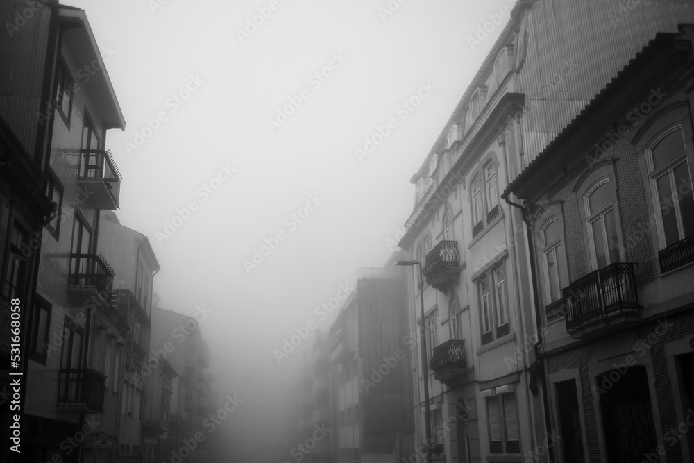 View of a deserted street in the early morning in dense fog. Porto, Portugal. Black and white photo.