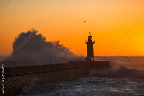 View of the Lighthouse with huge wave at Atlantic ocean during amazing sunset, Porto, Portugal.