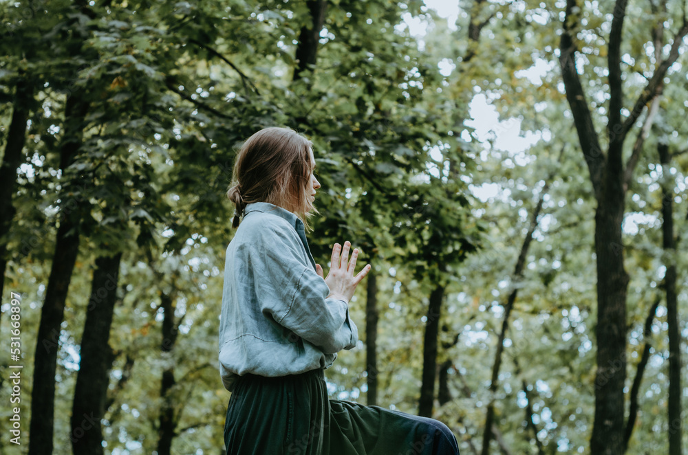 Woman in early fall forest with namaste prayer hands at chest Woman in early fall forest with namaste prayer hands at chest