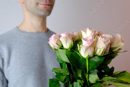 close-up of bouquet of white, pink roses in hands of young man, brought flowers on date with girlfriend, gives to mom, concept of mother's, Valentine's day, birthday, declaration of love