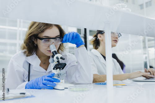 Fototapeta Naklejka Na Ścianę i Meble -  female researcher, medical scientist or doctor working and checking sample of virus using microscope in modern lab in laboratory, chemist developing concept