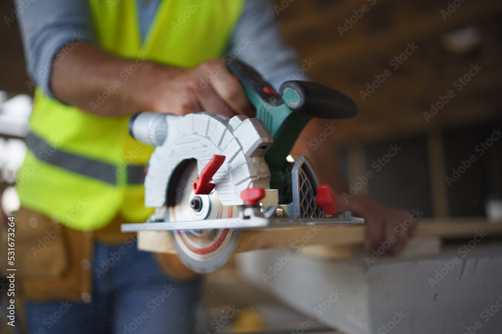 Close-up of construction worker working with eletric saw inside wooden construction of house, diy eco-friendly homes concept. Close-up of construction worker working with eletric saw inside wooden construction of house, diy eco-friendly homes concept.
