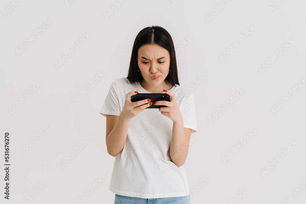 Asian displeased woman playing video game on cellphone Asian displeased woman playing video game on cellphone