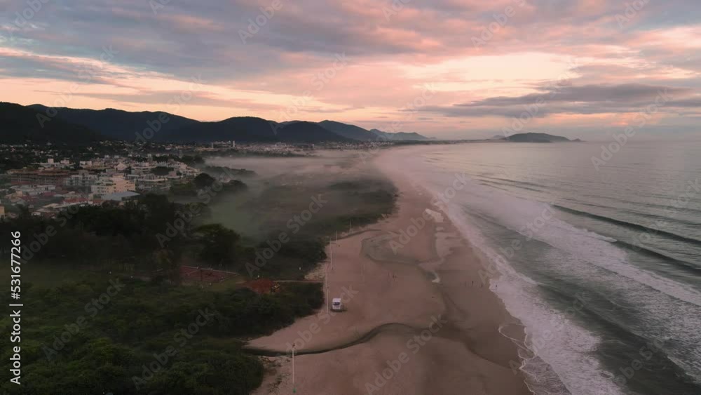 Campeche beach with morning fog and ocean with sunrise lights in Florianopolis Campeche beach with morning fog and ocean with sunrise lights in Florianopolis