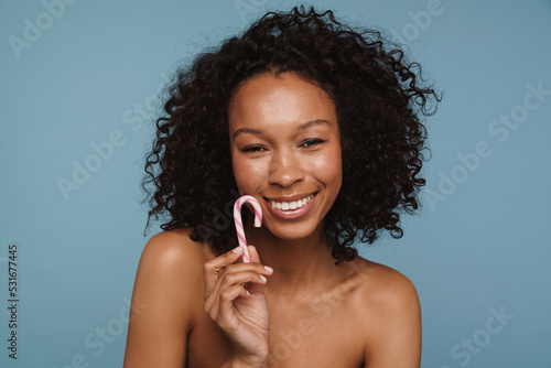 Shirtless black woman laughing while posing with candy