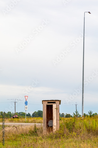 Wooden outhouse in a field, near a road in Ukraine