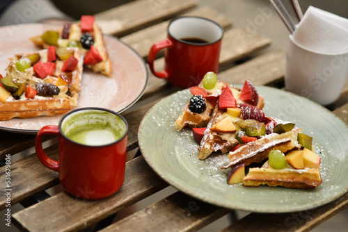 Belgian waffles with fruits and coffee on a wooden table in a cafe