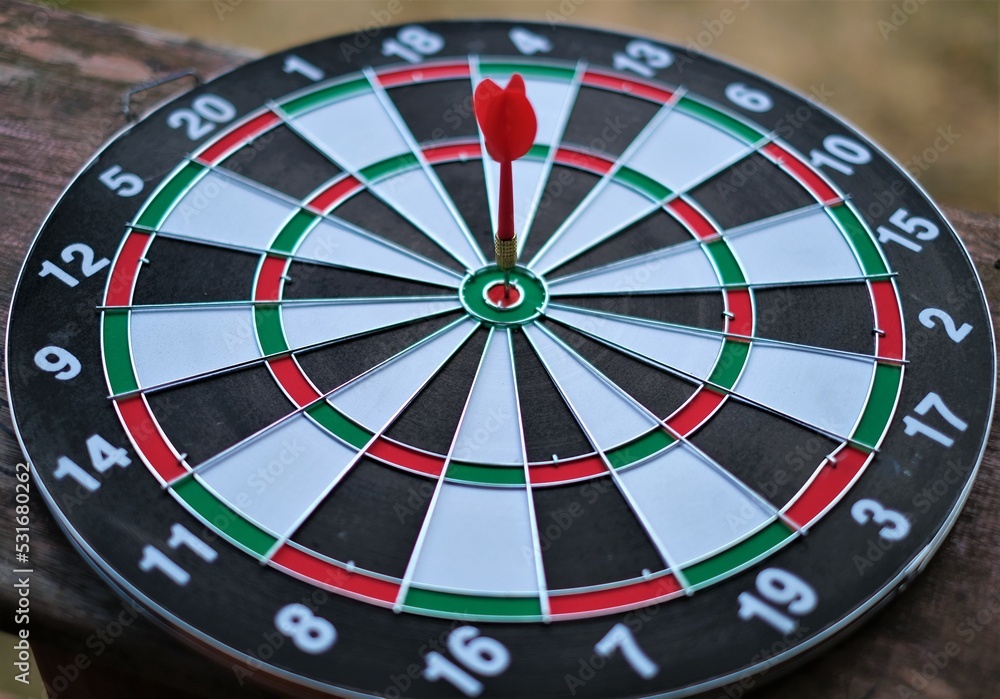 Red dart arrow hitting in the target center of dartboard Target hit in the center. Red dart arrow hitting in the target center of dartboard Target hit in the center.