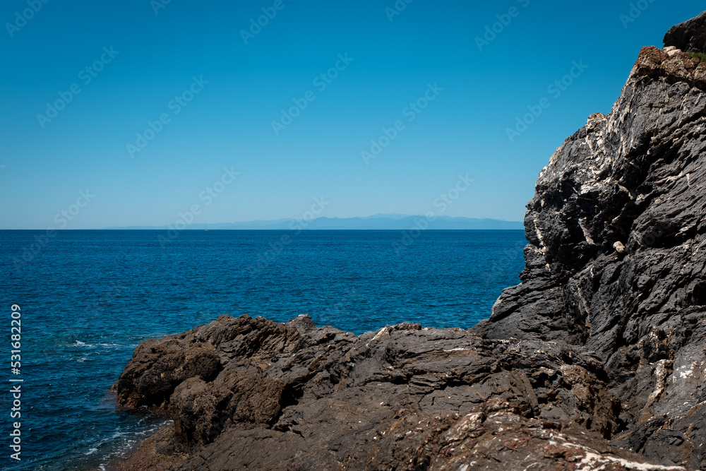 Rocky outcropping and deep blue sea off the coast of the Italian city of Camoglia on the Ligurian Sea.