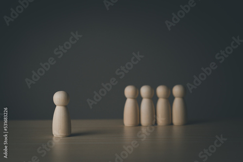 Leadership concept Selection of talented people. Selection of personnel in the organization. Wooden man model among people on black background. Wooden doll. Wooden peg doll. Wooden puppet.
