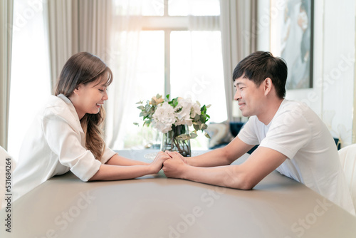 marriage couple holding hands looking in the eyes. happy handsome husband and beautiful wife enjoy watching each other eyes while touch hands together. boyfriend and girlfriend living in good house