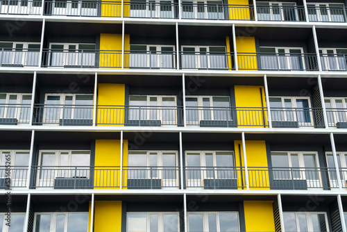 the facade of a modern multi-storey building, windows and balconies, yellow and black walls, the concept of urbanism and city construction