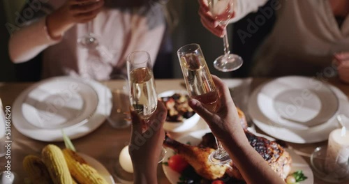A group of people clink glasses of champagne over a festive table where roasted turkey is served. Top view