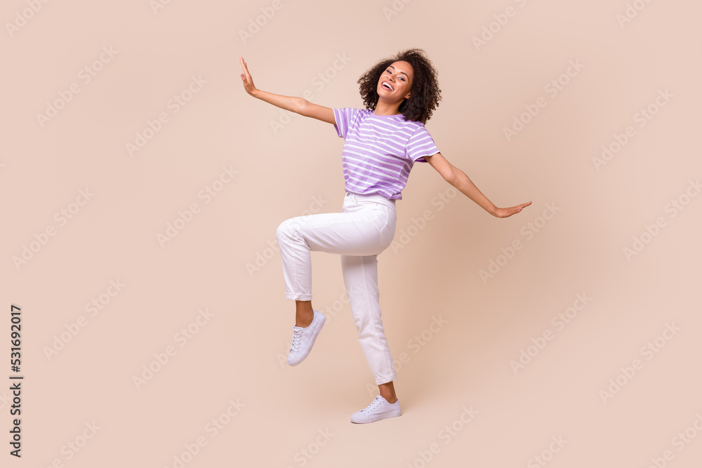 Full length photo of gorgeous cheerful woman dressed striped t-shirt white trousers peaceful flight isolated on beige color background Full length photo of gorgeous cheerful woman dressed striped t-shirt white trousers peaceful flight isolated on beige color background