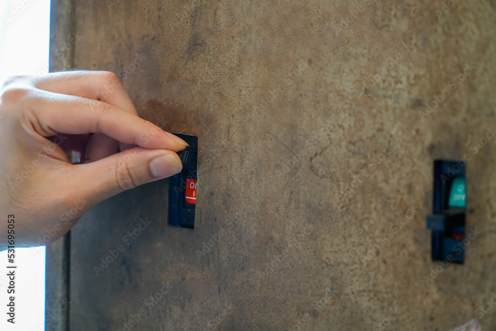 Foto de Male electrician turns off the power for an outlet at an industrial breaker box