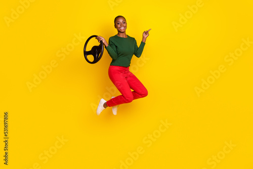 Full length photo of funky positive lady dressed green shirt jumping high riding auto empty space isolated yellow color background © deagreez
