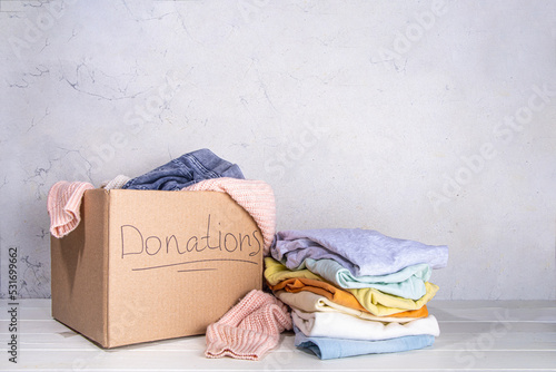 Wall Mural Donation box with clothes, toys and food on white table background
