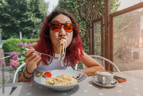 The girl is in a funny hurry and eats Italian pasta in a cafe. The concept of good manners and rules of etiquette on the first date photo