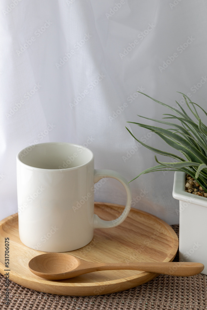 Fototapeta premium White mug mockup on wooden plate in front of white curtain.