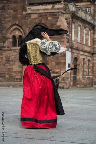Strasbourg - France - 17 September 2022 - Portrait on back view of woman wearing a traditional medieval costume walking in the street photo