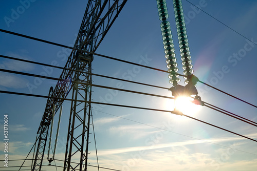 High voltage tower with electric power lines divided by safe guard bushing transfening safely electrical energy through cable wires. Electricity transmission on long distance concept
