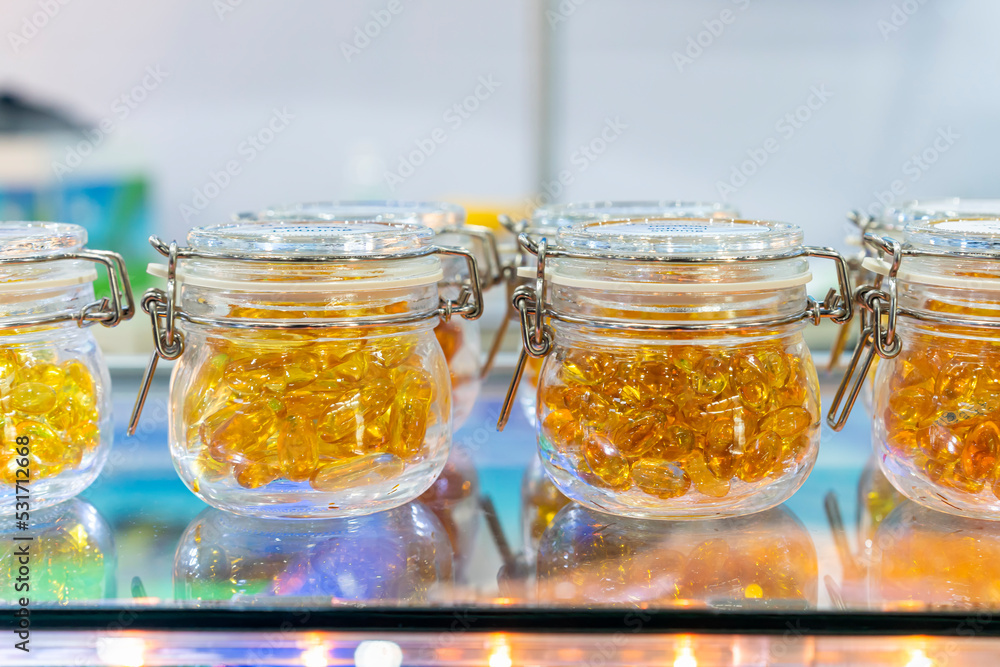 Many cod liver oil soft capsule or other look like in clear glass jar on the shelf Many cod liver oil soft capsule or other look like in clear glass jar on the shelf