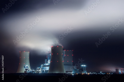 Panorama eines Kohlekraftwerks bei Nacht mit Rauch aus Kühltürmen