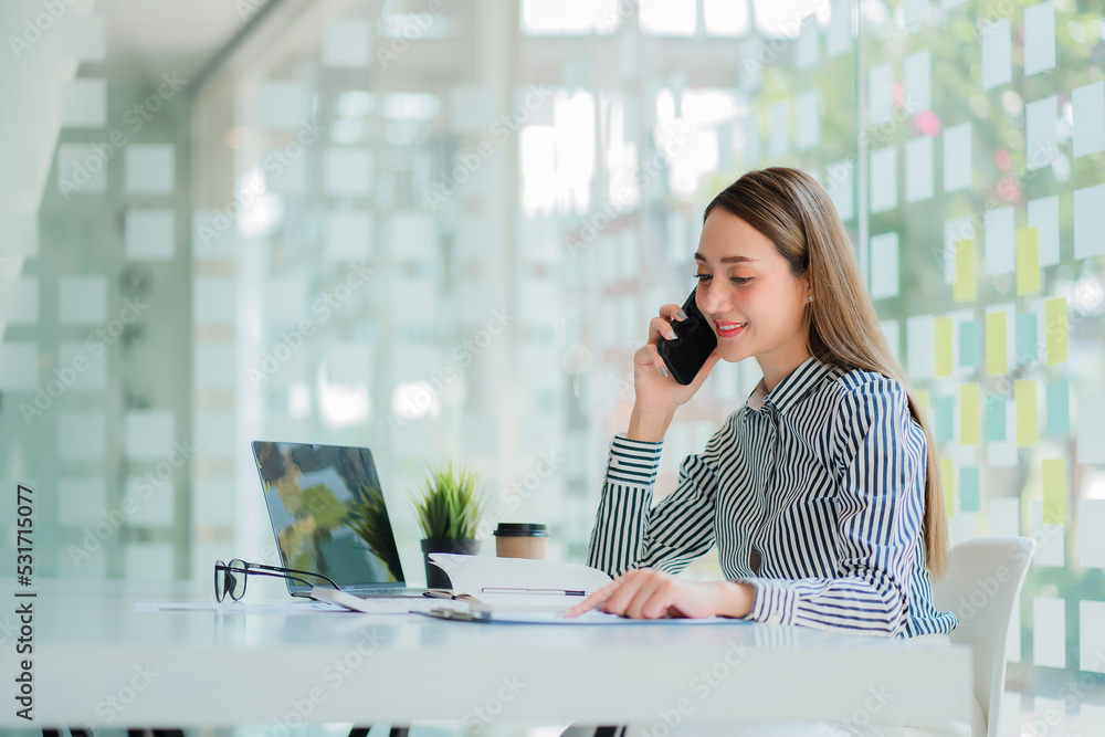 Asian businesswoman in a formal suit in the office is happy and cheerful while using a smartphone to work, financial accounting, analytical concept. Asian businesswoman in a formal suit in the office is happy and cheerful while using a smartphone to work, financial accounting, analytical concept.