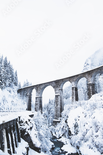 Mountain landscape with Sainte Marie bridge covered with snow in Les Houches, Chamonix valley, Eastern France. Viaduct bridge built to carry a railway over water.