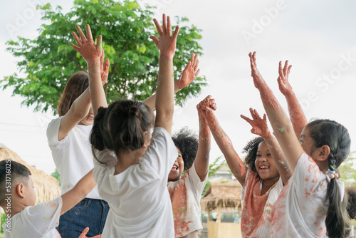 Group of children playing colourful water colours and colour stain on hand and dress. Happy children playing and painting water colour in class at school