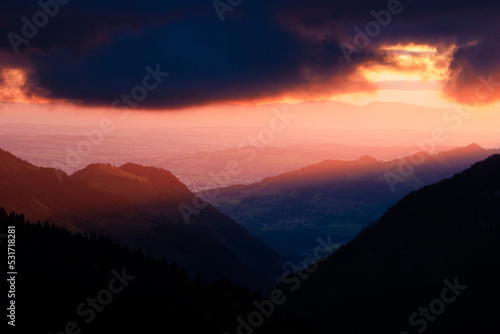 dramatic sunset with clouds and the sun in the Alpine foothills of Fribourg