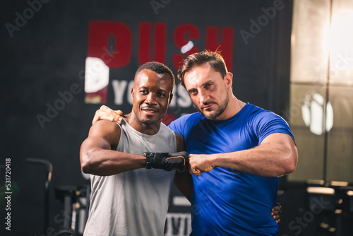 Handsome men pose after exercise fitness class mixed martial arts training instructor. Attractive young muscular men bumping fist working out training together at the gym. fitness and healthy concept.