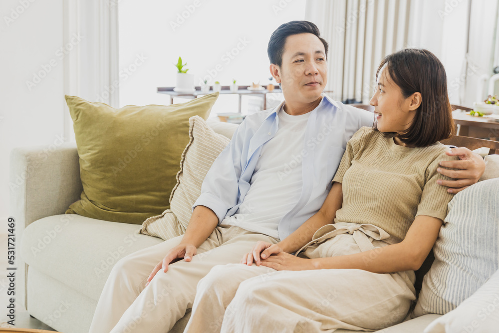 Happy wife and husband sit and talk on sofa at home