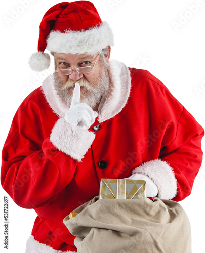Image of santa claus with finger on lips holding christmas presents