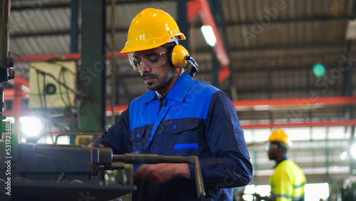 Professional industrial engineer, technician, factory worker wear hard hat, safety glasses. While checking, set up, control machine heavy industry factory. Employee working in manufacturing facility.