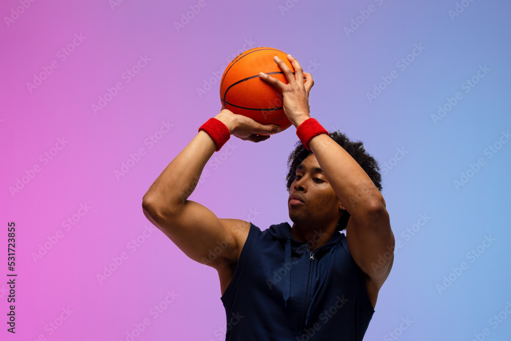 Image of biracial basketball player throwing basketball on pink to blue background
