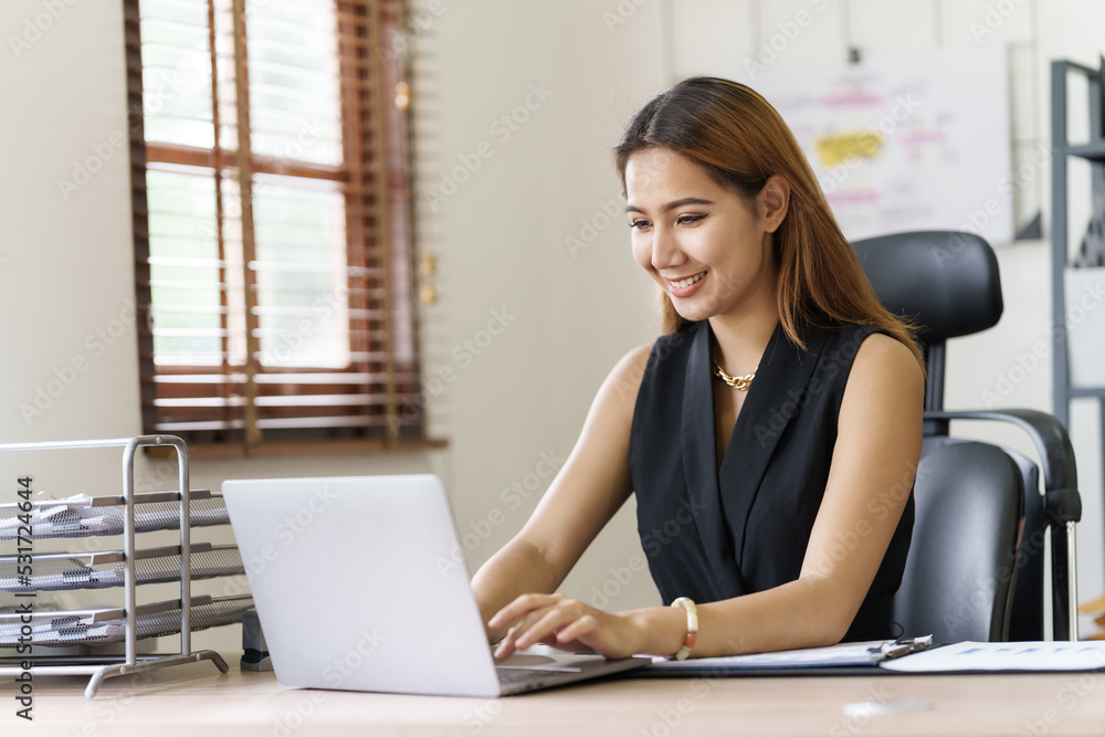 Asian thai businesswoman using laptop at working desk in modern office, busy job but feeling happy. Asian thai businesswoman using laptop at working desk in modern office, busy job but feeling happy.