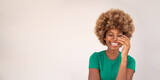 Happy attractive young dark-skinned woman in green t-shirt and afro hairstyle laughing with her eyes closed. beige background long horizontal banner with copy space. delight and enjoyment of  moment