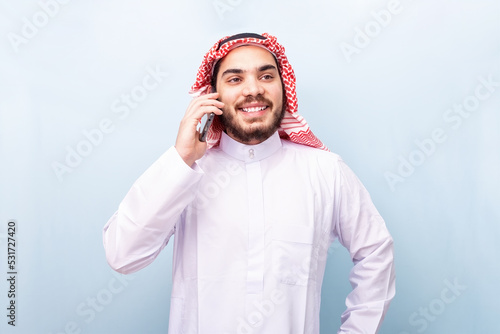 Young arabian, smiling with traditional wear, using the mobile phone. photo