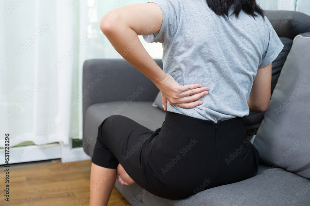 Asian woman aching back spinal pain from stress of injury, painful ache stress muscle cramp, body upper muscle problem, indeed of medical physical therapy concept, home living room coach lifestyle Asian woman aching back spinal pain from stress of injury, painful ache stress muscle cramp, body upper muscle problem, indeed of medical physical therapy concept, home living room coach lifestyle