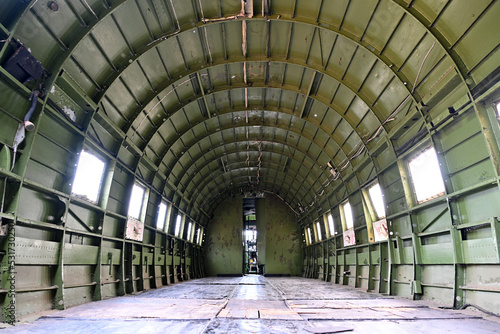 Fuselage of the inside of a military green plane during the war era showing the empty space that troops were carried in. Paratroopers would jump from this plane and sky dive to the ground
