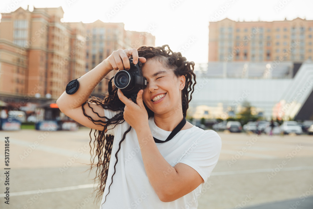 A young photographer with a professional outdoor camera. Space for text. a girl with dreadlocks photographs the city landscape. photo.