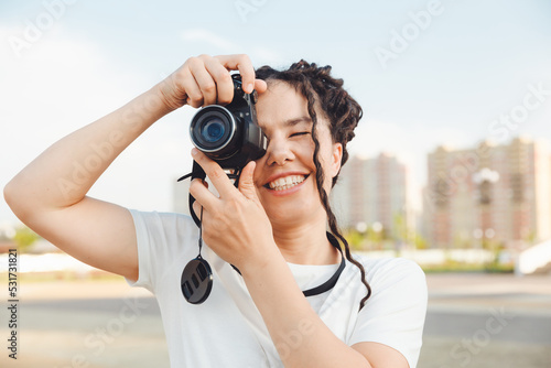 A young photographer with a professional outdoor camera. Space for text. a girl with dreadlocks photographs the city landscape. photo.