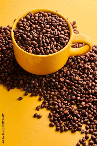 Cup of freshly brewed roasted coffee beans on yellow background © amixstudio