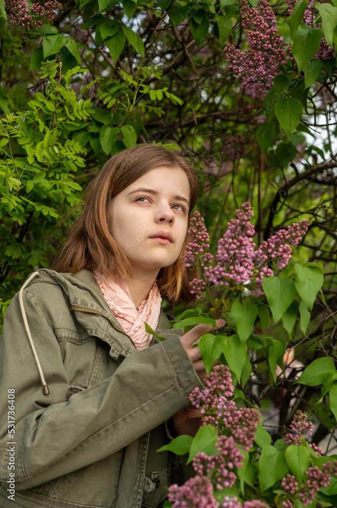 Portrait of a young teenage girl in the garden, a bush of blooming lilacs in the spring. High quality photo Portrait of a young teenage girl in the garden, a bush of blooming lilacs in the spring. High quality photo