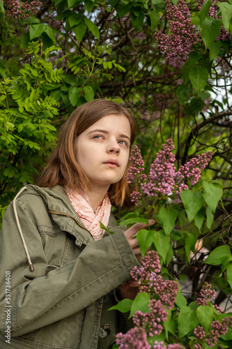 Portrait of a young teenage girl in the garden, a bush of blooming lilacs in the spring. High quality photo