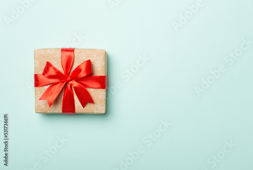 Gift box with red ribbon bow on color background, top view © Liami